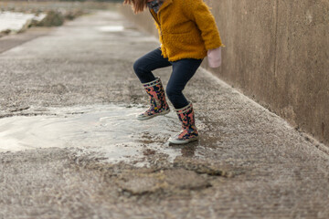 child splashing in a puddle of rain