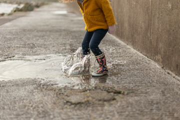 child splashing a puddle of rain