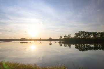 Gravel path running along lake shore at sunset with golden light, Po River, Piaceza, Italy