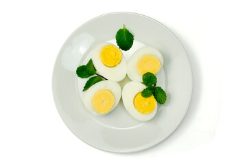 Four pieces of half sliced hard boiled eggs with mint leaves in white plate on white background top view, clipping path, stack. Preparing to cook.