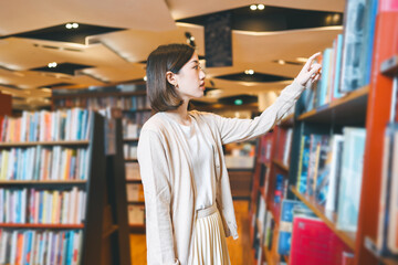 Portrait of young adult southeast asian woman reading book at bookstore shop