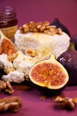 Fototapeta premium Whole and cut figs with cottage cheese and honey on a purple background. Mediterranean cuisine