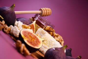 Whole and cut figs with cottage cheese and honey on a purple background. Mediterranean cuisine