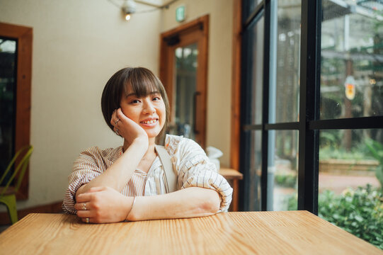 車椅子に乗った日本人女性がテーブルで頬杖をついて休んでいる