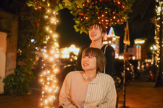 夜に車椅子に乗った日本人女性が友人と夏の沖縄旅行を楽しんでいる