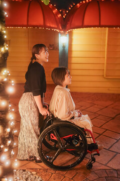 夜に車椅子に乗った日本人女性が友人と夏の沖縄旅行を楽しんでいる