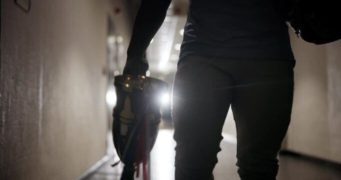 Hands, trophy and person in stadium for American football with helmet, winning and success in corridor. Player, sports and prize for goals, celebration and competition with safety gear in hallway