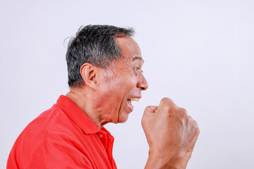 Fototapeta premium Senior Asian man in red t-shirt celebrating success with arms raised isolated on white background