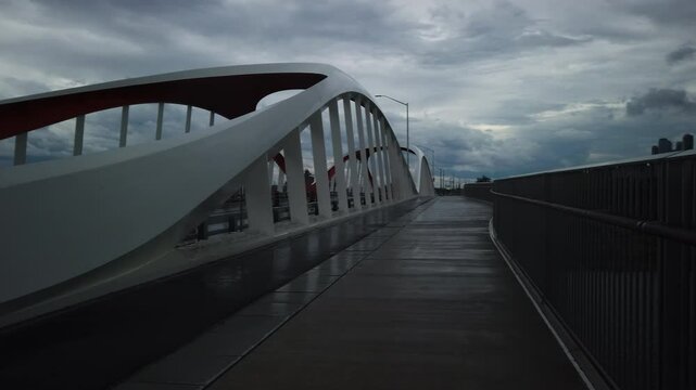 Rainy day view of Commissioners Street Bridge in Toronto with wet bike path and buildings in the background, pan right