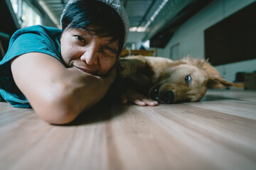 Obraz premium Soft focus blurs the face of the person, Selective focus A real Asian man takes a selfie golden retriever. The dog is playing together Looking funny at the camera at home.
