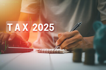 Hands are recording and using a calculator to calculate taxes to file taxes online for 2025 new...