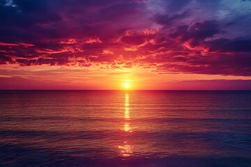 A vivid colorful sunset over a calm ocean with rich hues of red purple and gold