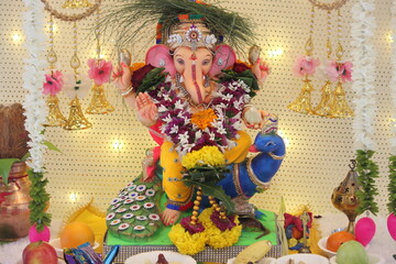 lord ganesha idol on Ganesh chaturthi. little Ganpati is sitting a beautiful peacock in the idol. the temple is decorated with lights and flowers. On the occasion on Ganesh Stapna on chaturthi 