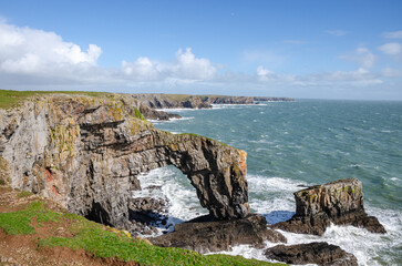 Close-up of rocky sea stacks in Wales being lashed by ocean waves.