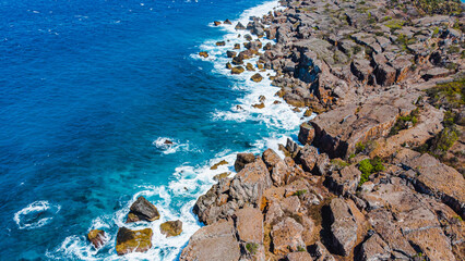 Ocean waves in bright turquoise hit a rugged shore, waves frothing and crashing fiercely © Balnyes Visuals