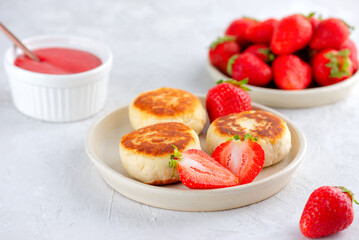 Fried cheesecakes, syrniki, cheese pancakes with berries, jam, cashew, and tofu on a table, vegan food. Sugar, lactose and gluten free.