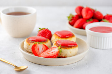 Cheesecakes, syrniki, cheese pancakes with berries, jam, cashew, tofu and cup of tea on a light table. Vegan food. Sugar, lactose and gluten free.