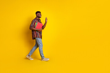 Full size profile photo of nice young man walk wave empty space wear shirt isolated on yellow color background