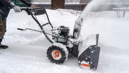 janitor man removes snow with a snow blower