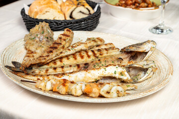 Mixed grill of fresh fish served on a large oval white restaurant plate.