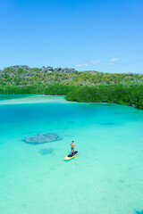 Stand up paddle board man paddleboarding on blue lagoon standing happy on paddleboard on blue water.