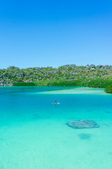 Man standing on sup board and enjoying turquoise transparent water and coral reef.