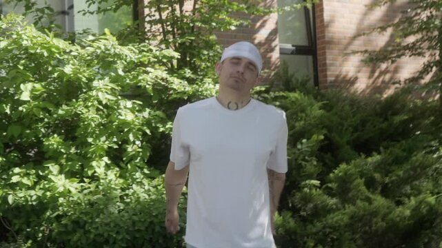 A man in a white shirt performs playful dance moves, mimicking gun gestures with his hands. His carefree attitude, energy, and expressive style reflect confidence, individuality, and a laid-back vibe.