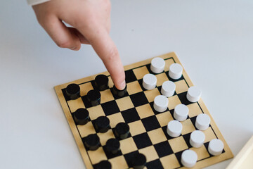 Teenage Girl and Boy Playing Board Game checkers In Living Room. Playing a board game on a white ottoman. They are both focused on the game. Children Playing a Checkerboard Game Indoors