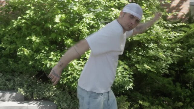A man in a white shirt and durag performs an expressive freestyle dance. His dynamic performance emphasizes individuality, confidence, and self-expression through rhythmic body language.