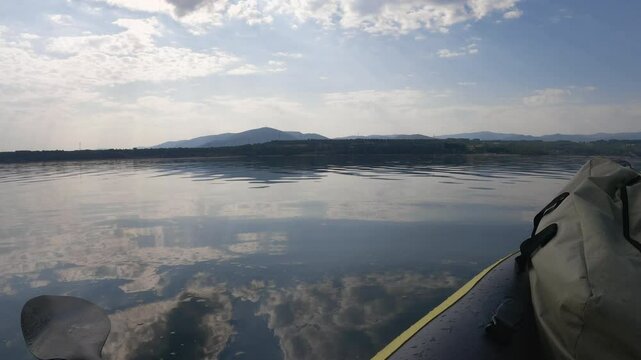 Panning of the Barcena reservoir from an inflatable kayak that is floating on the water in the center of the reservoir during sunrise enjoying the landscape