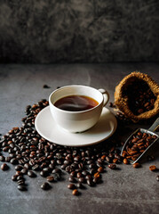 Americano coffee cup and roasted coffee beans falling in a burlap sackon gray background, Black coffee cup aromatic