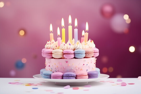G&acirc;teau d'anniversaire festif et color&eacute;, d&eacute;cor&eacute; avec des macarons pastel et des bougies allum&eacute;es, sur un fond rose doux, ambiance joyeuse et gourmande avec ballons roses en fond avec effet bokeh