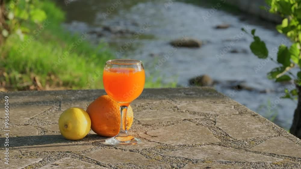 Poster orange juice on the stone table with flowing stream in background
