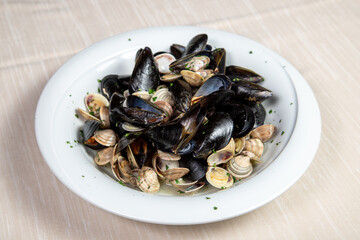 Mussels and clams soup in a withe dish.