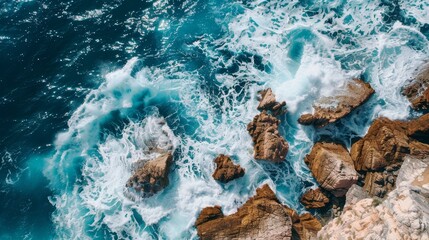 High-angle shot of waves crashing on a rocky coast, northern region, clear blue sea, sunny day