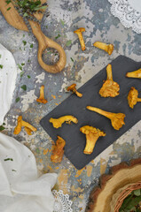 Golden chanterelles mushrooms on a cutting board, green herbs, white napkins and tablecloth. Top view food. Autumn.