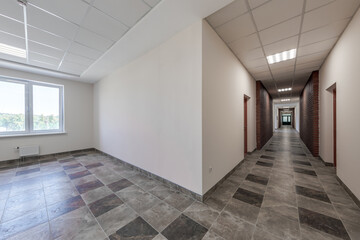 empty long corridor with red brick walls and doors in interior of modern apartments or office