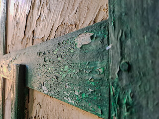 photo features a piece of wood with peeling teal paint. The texture is rough and aged