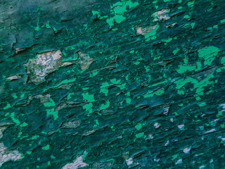 photo features a piece of wood with peeling teal paint. The texture is rough and aged