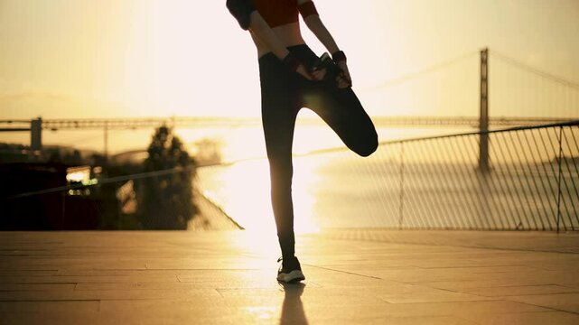 A girl warms up before an evening jog along the coast. Motivational video in sun rays for social network