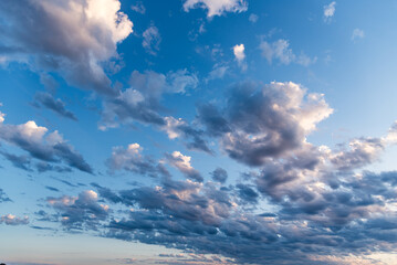 Obraz premium Beautiful white puffy clouds against blue sky during dramatic sunset