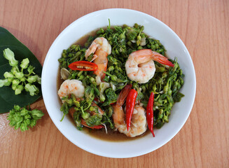 Stir-fried shrimp with Telosma cordata flowers, garnished with red chilies on top. Place fresh flowers and leaves. On a light wooden table