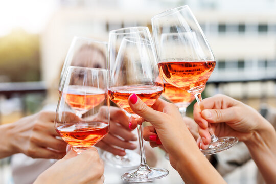 Close-up many female woman hands hold clinking rose wine glass celebrate toast party terrace warm sunset sun background. Girl friend enjoy drink champagne cocktail bachelorette event outdoor cafe bar
