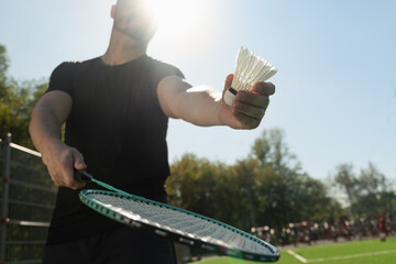 Man playing badminton on floor sport court in sunny shadow. Outdoors. Close up.
