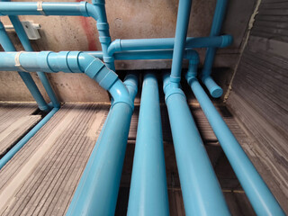 A bright blue pipes attached to a solid concrete wall