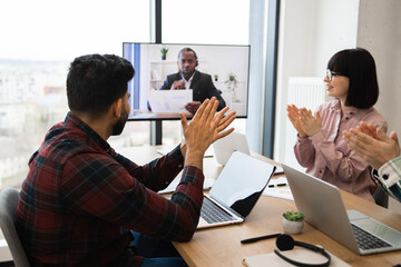 Office colleagues in video conference call applauding during virtual meeting. Team celebration of successful project completion. Online business communication and remote collaboration.