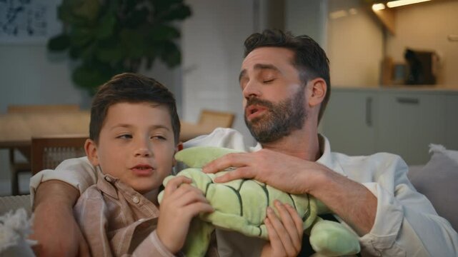 Closeup daddy kid bonding evening apartment interior. Small child holding toy