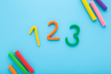 Colorful 123 numbers created from modeling clay on light blue table background. Pastel color. Time...