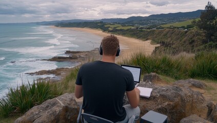 Fototapeta premium A man is sitting at his laptop on the beach