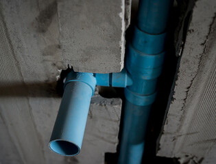 A bright blue pipes attached to a solid concrete wall